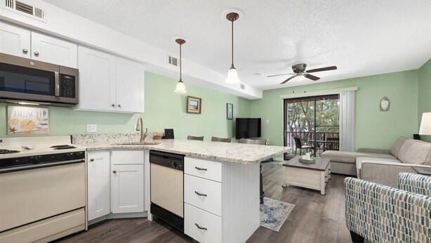 A compact kitchen with white cabinets, a microwave, and a dishwasher. There is a dining area with a table and chairs, and a living room with a sofa and a TV. - Close to the Boardwalk, Jolly Roger Amusement Park With a Pool! (Ocean City)