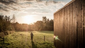 A person walking on a grassy field towards a wooden building. - Kalmdown Cabin - Antwerp (Wuustwezel)