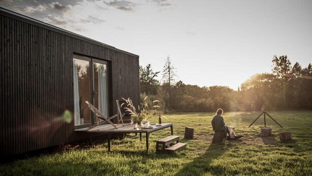 A modern house with a large sliding glass door, a wooden deck, and a grassy yard. - Kalmdown Cabin - Antwerp (Wuustwezel)