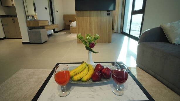 Un soggiorno moderno con un tavolo da pranzo imbandito di frutta e bevande, un divano e una televisione.