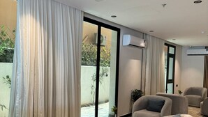 A modern living room with large windows, a flat-screen TV, and a small side table. - Hadab Tabuk (Tabuk)