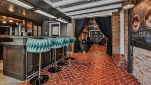 Een bar met een geplaveide vloer, een toog en een blauwgroene barkruk.
