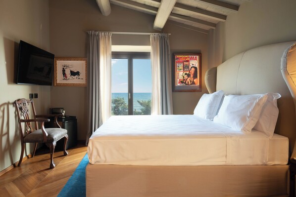 A bedroom with a large bed, a chair, a television, and a poster on the wall.