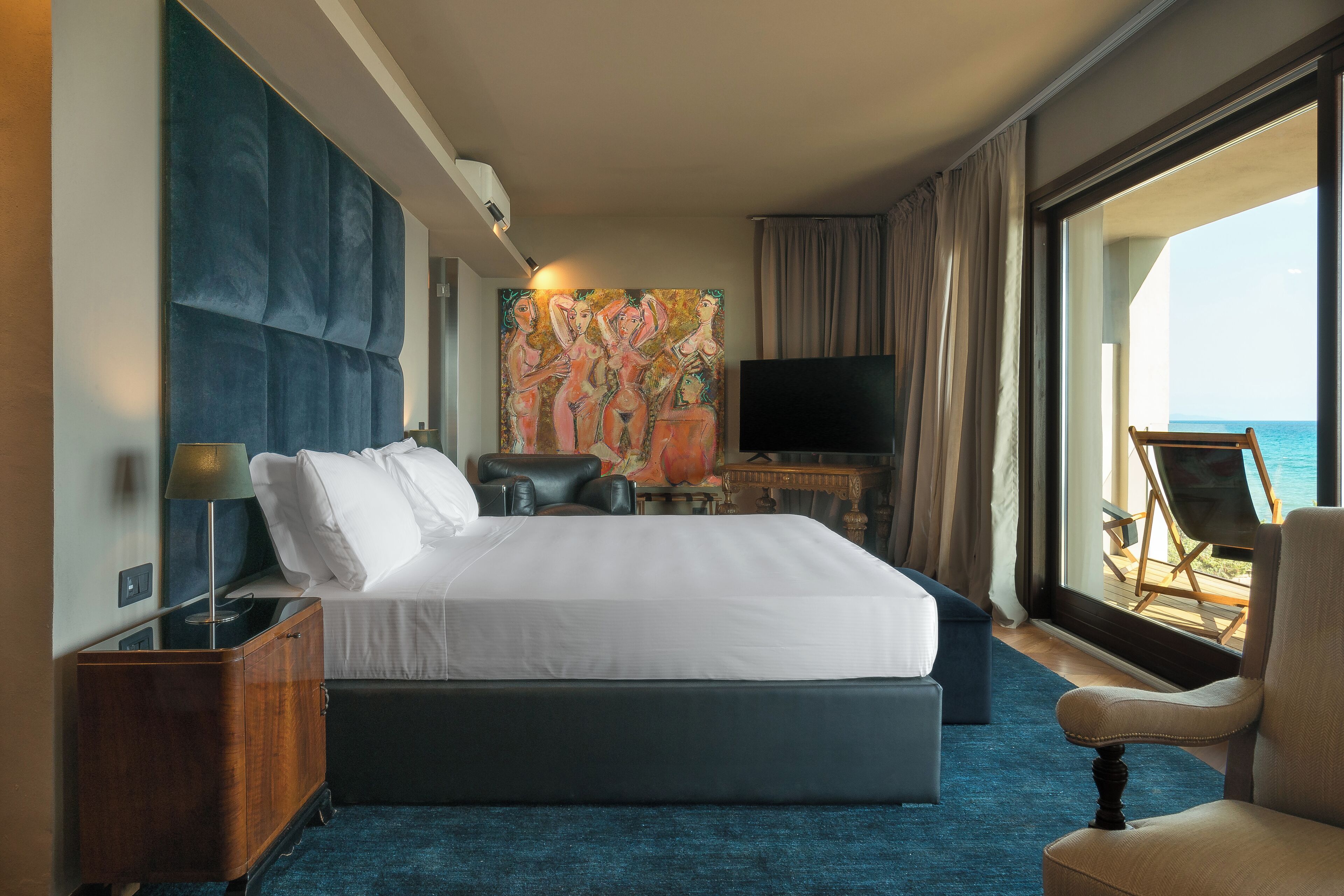 Habitación de hotel con una cama grande, televisión, escritorio y vista al mar.
