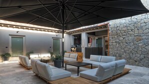 An outdoor seating area with a stone wall, a wooden table, and a large umbrella.