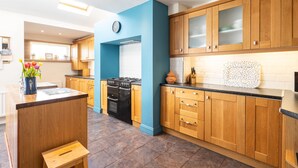 Una cocina moderna con armarios de madera, estufa a gas y una pared azul decorativa.