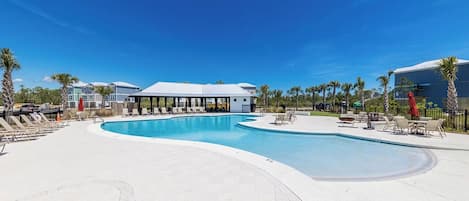 A swimming pool with lounge chairs and a covered seating area.