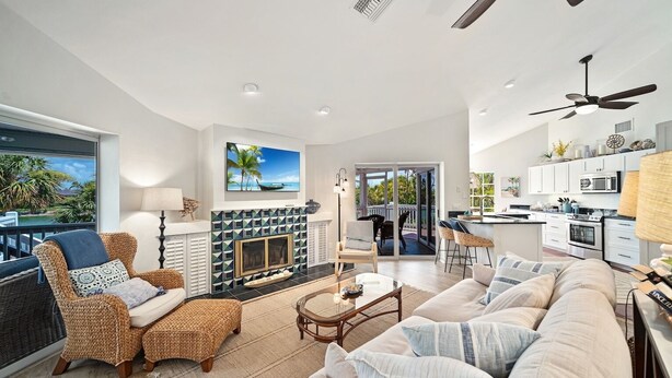 A spacious living room with a fireplace, a dining area, and a kitchen. - Island time. 10 min walk to beach, heated pool, wide water views.  Pet friendly! (Sanibel)