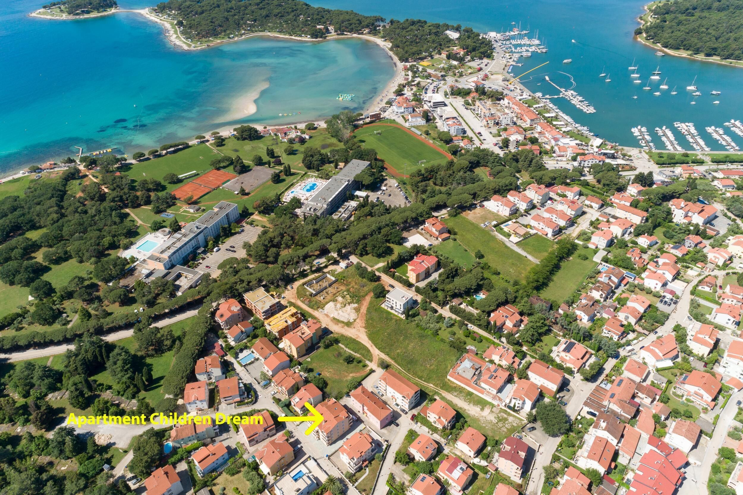 Vista aérea de una zona residencial costera con casas y un gran edificio que dice 'Apartment Children Dream'.