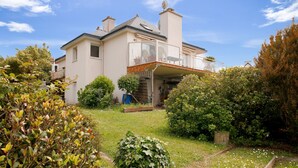 A two-story house with a balcony, surrounded by a garden with various shrubs and a lawn. - House for 6 with a view of the port of Dahouët (Pléneuf-Val-André)