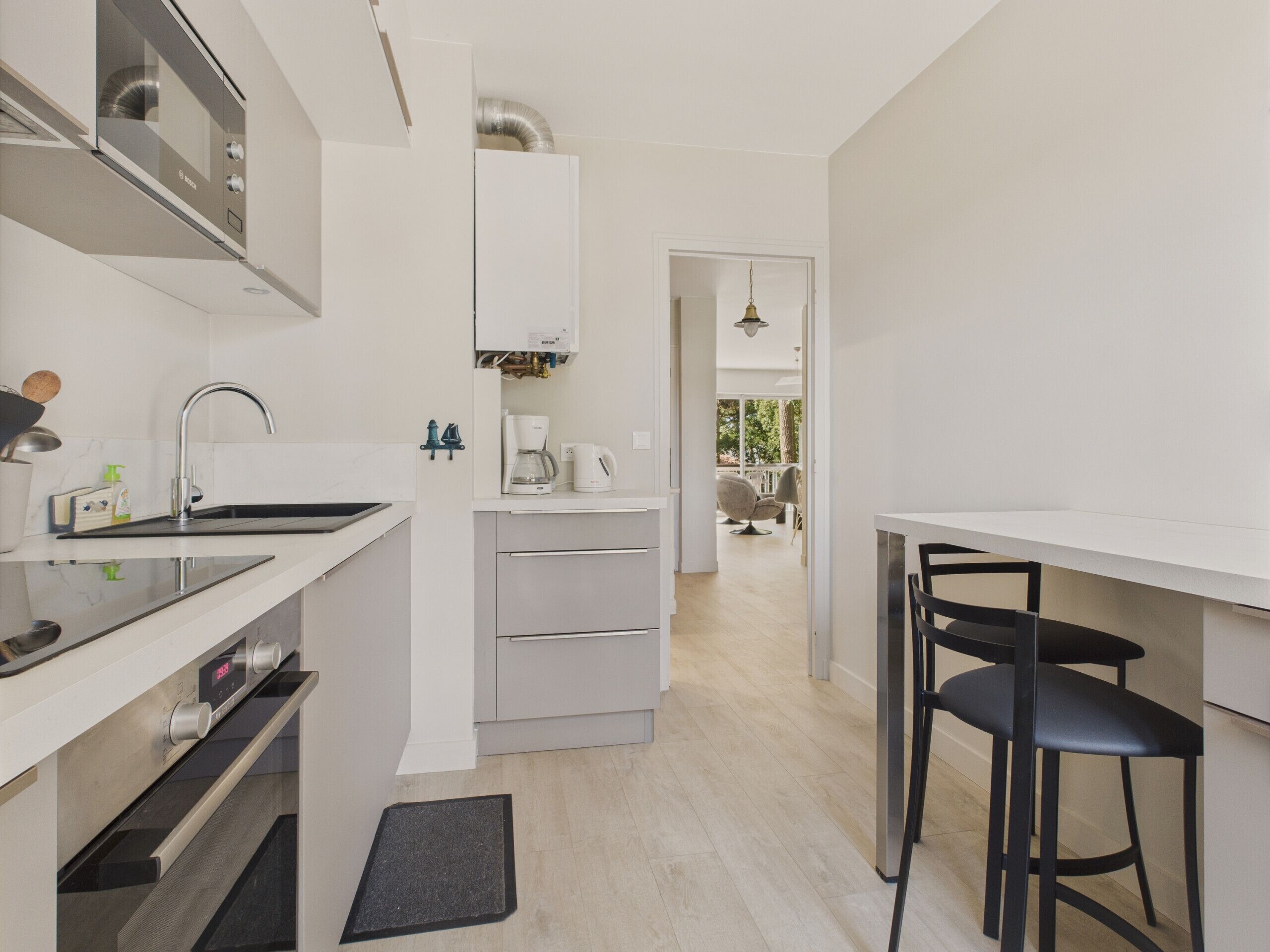 Una cucina moderna con forno integrato, macchina da caffè e lavello. È presente un'area pranzo con tavolo e sedie.