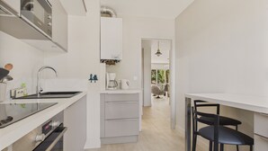 A modern kitchen with a built-in oven, a coffee maker, and a sink. There is a dining area with a table and chairs. - Appartment for 4 in the heart of La Baule (La Baule-Escoublac)
