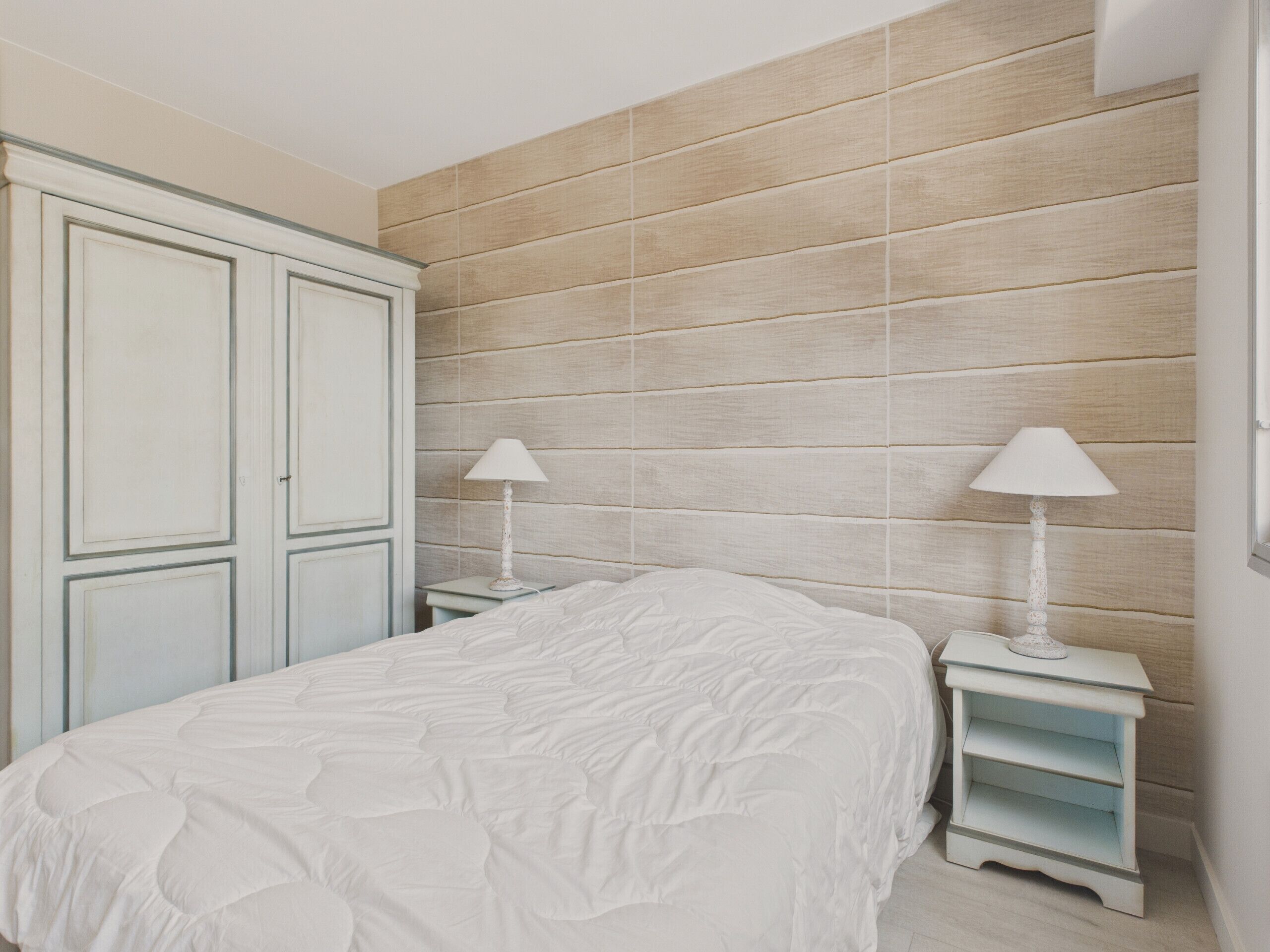 A bedroom with a bed, two bedside tables, and a wardrobe.