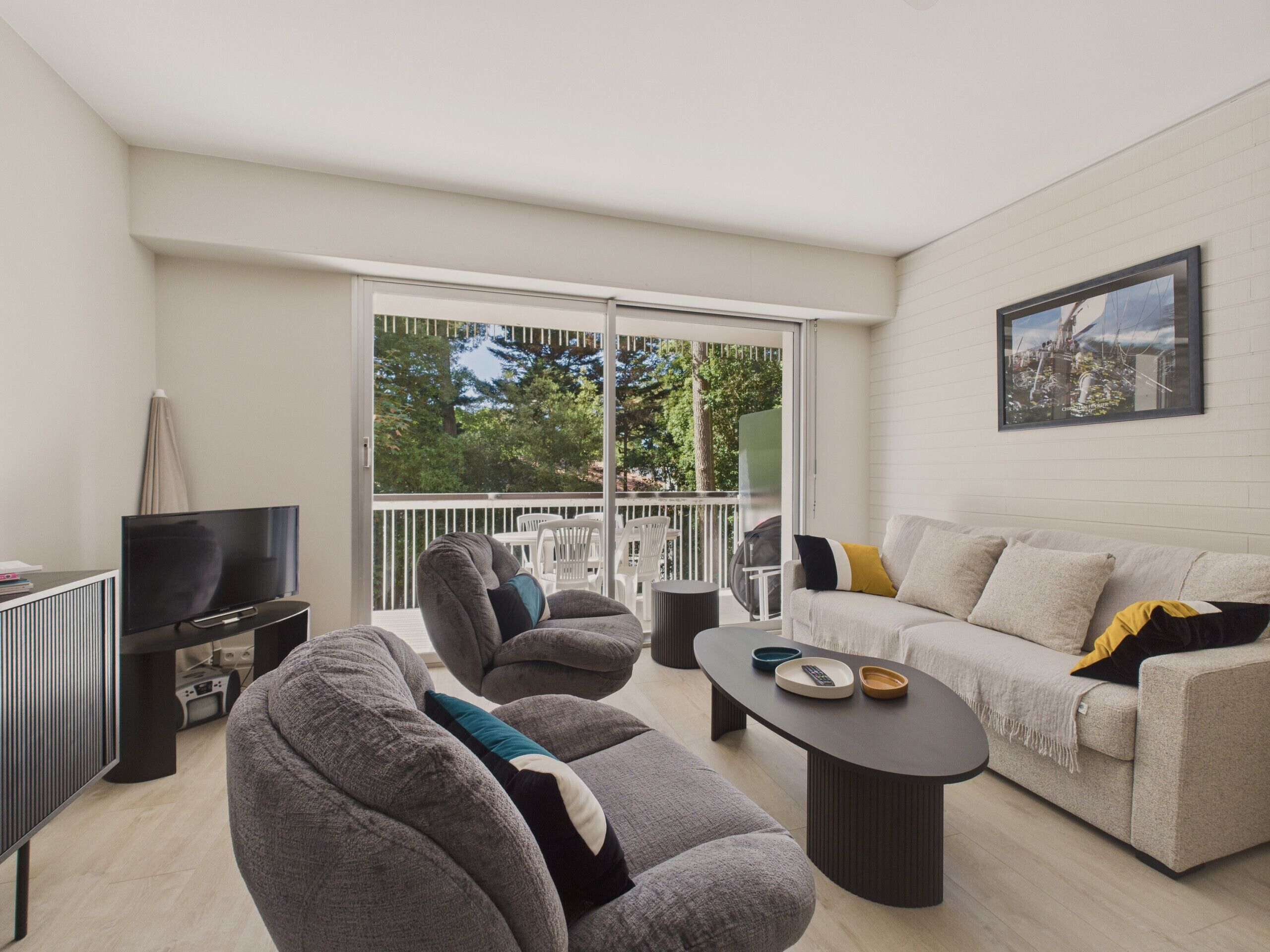 A modern living room with a sofa, armchairs, a coffee table, and a TV.