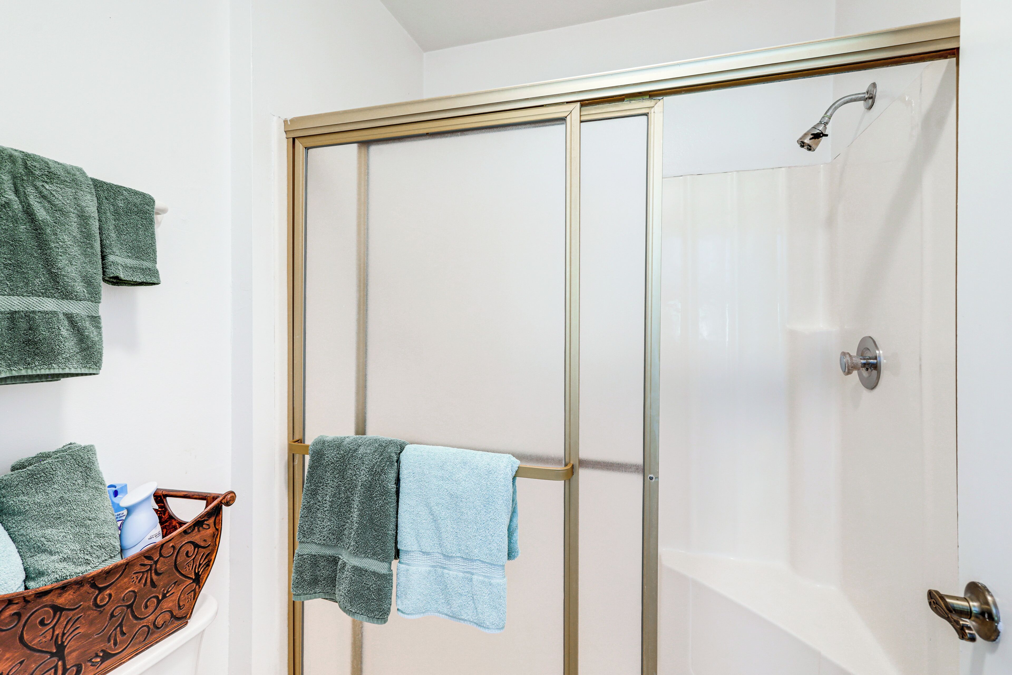 Une salle de bain avec une douche à parois de verre, une baignoire blanche et une baignoire en bois, ainsi que des serviettes.