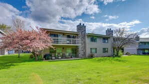 A two-story house with a stone chimney, a covered porch, and a well-maintained lawn. - Carbondale Condo w/ Balcony & On-site Fly Fishing! (Carbondale)