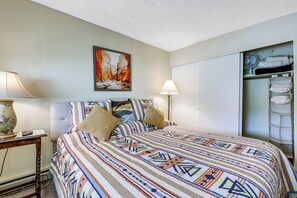 A neatly arranged bedroom with a bed, two bedside lamps, a painting on the wall, and a wardrobe with folded clothes. - Carbondale Condo w/ Balcony & On-site Fly Fishing! (Carbondale)