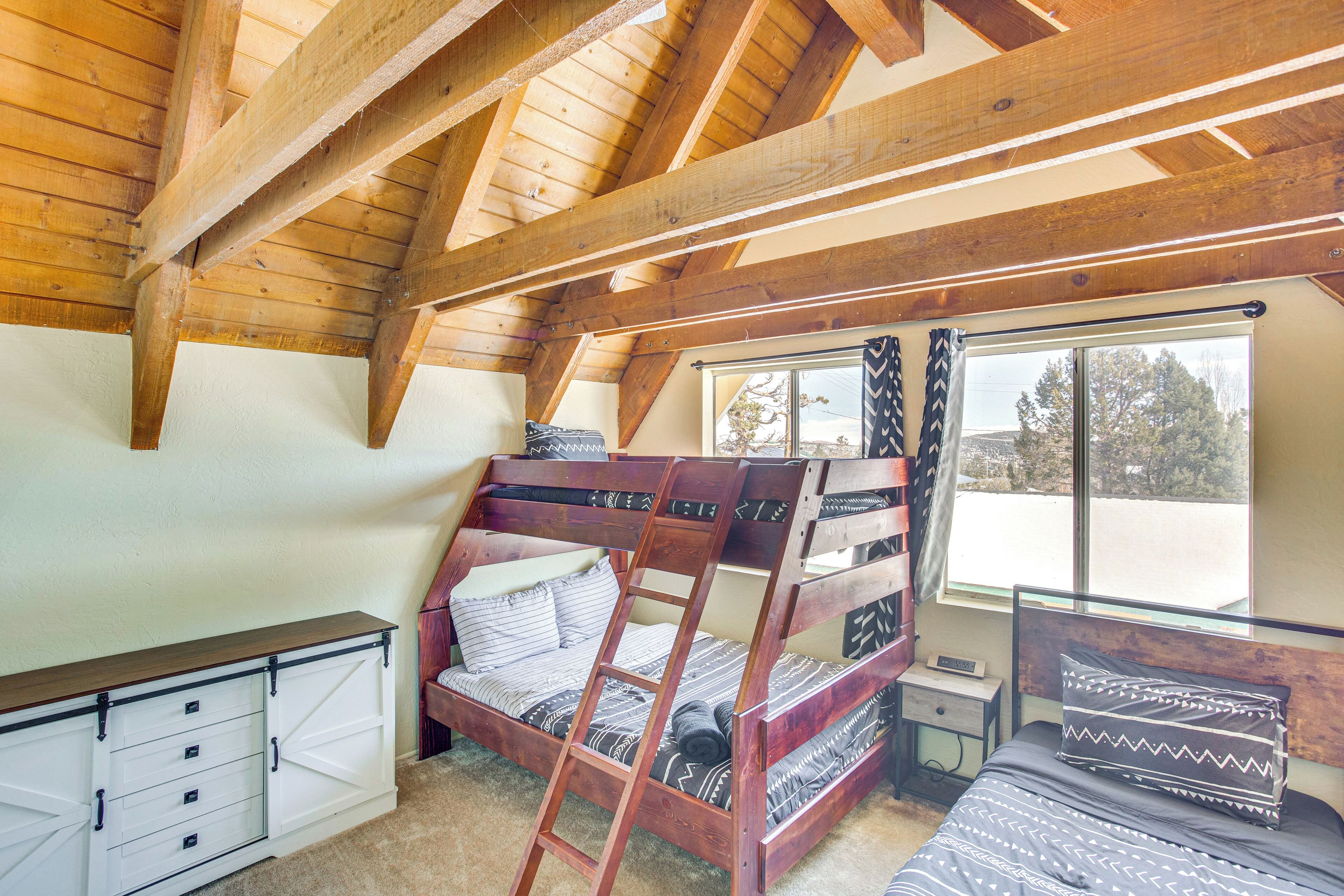 A loft-style bedroom with a bunk bed, a desk, and a window with curtains.