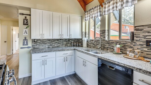 A modern kitchen with white cabinets, granite countertops, and a dishwasher. - 7 Mi to Big Bear Lake: A-frame Home w/ Deck! (Sugarloaf)