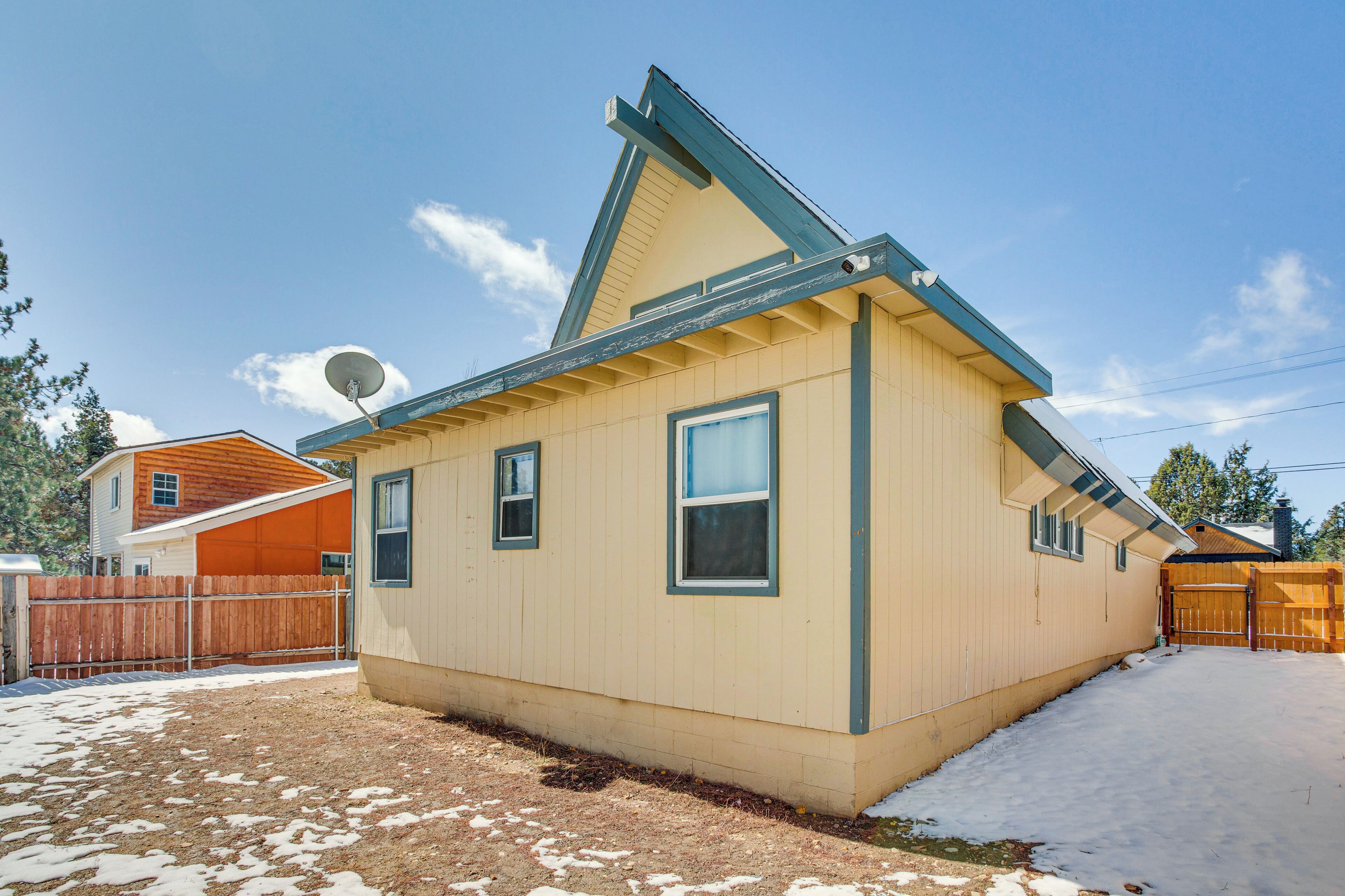 A single-story house with a gabled roof, a satellite dish, and a fenced backyard.