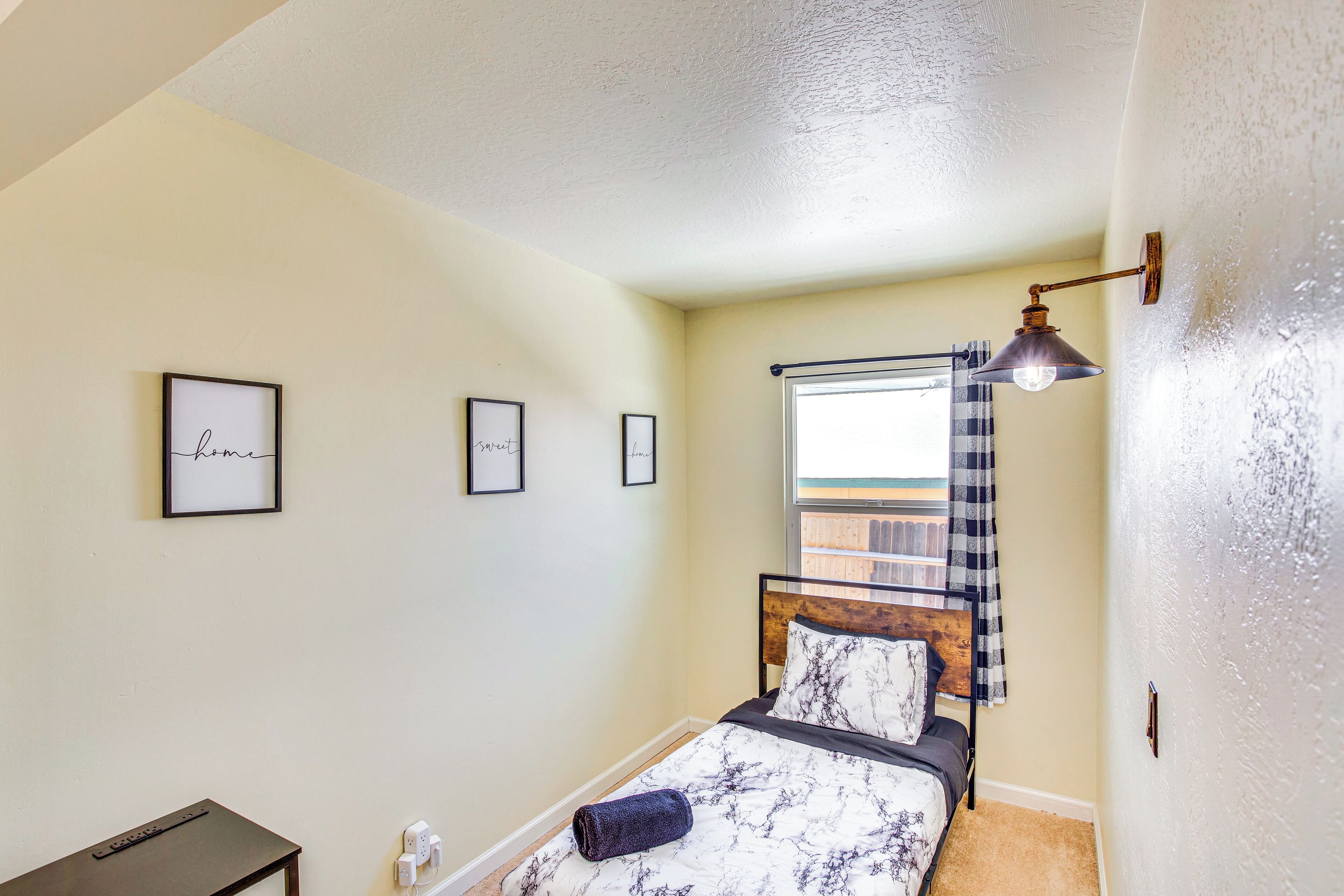 A bedroom with a bed, a bedside table, a lamp, and framed pictures on the wall.