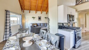 A dining area with a wooden ceiling, a kitchen with white cabinets, and a gray sofa. - 7 Mi to Big Bear Lake: A-frame Home w/ Deck! (Sugarloaf)
