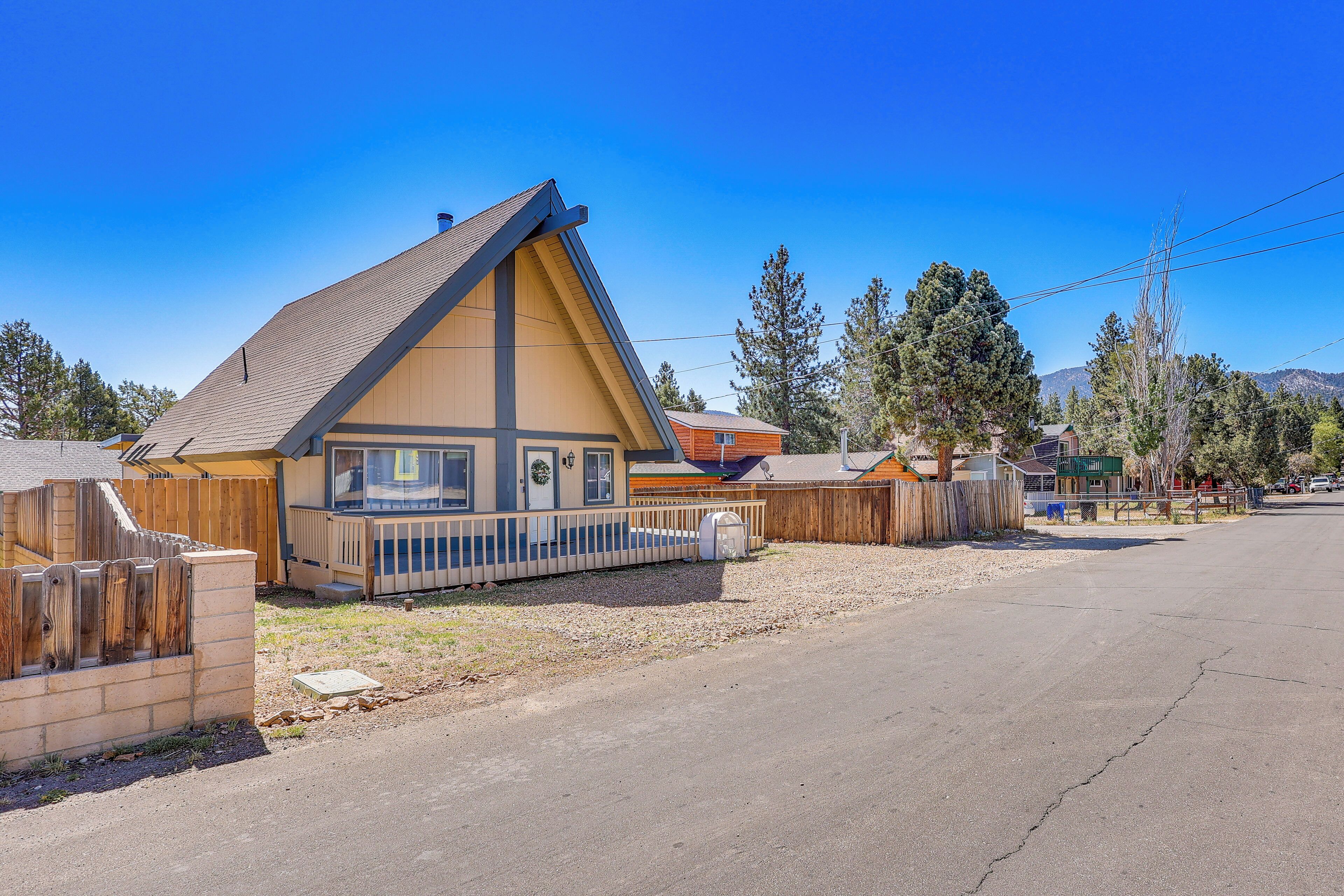 A single-story building with a sloped roof, a fenced yard, and a clear sky.