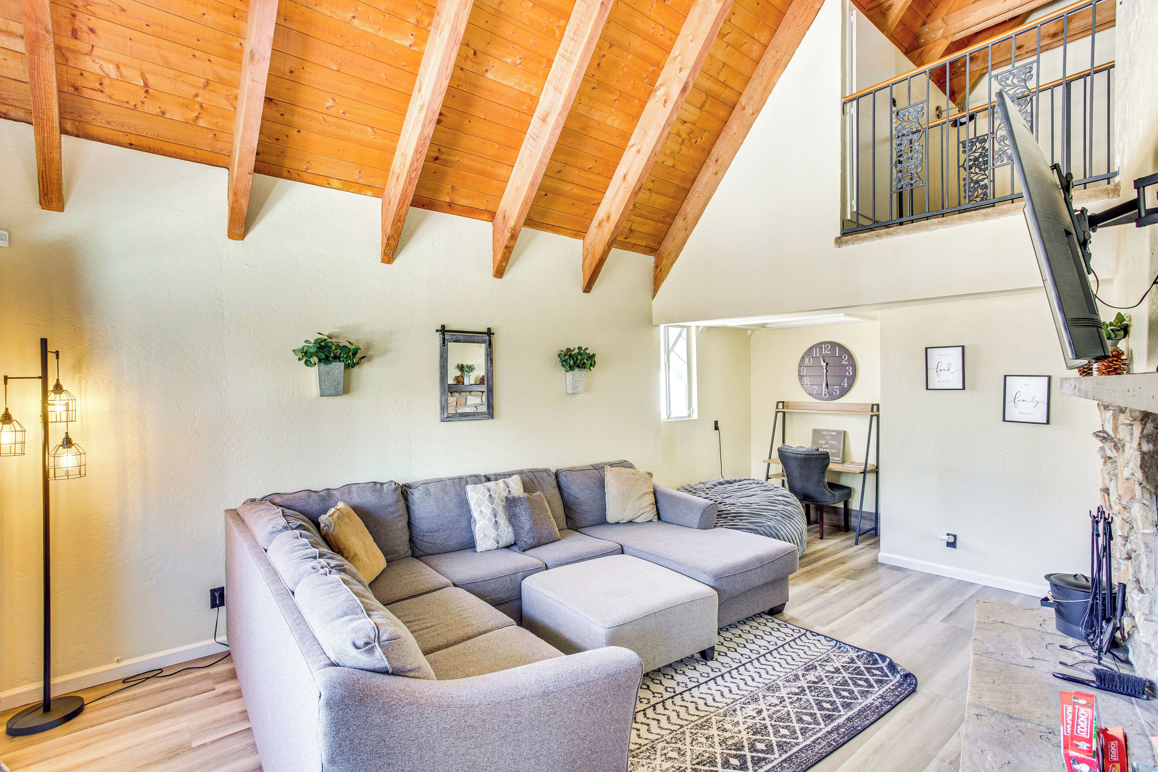 Una sala de estar amplia con un sofá modular grande, vigas de madera en el techo, una escalera a un nivel superior y una chimenea.