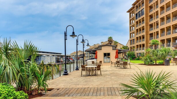 A patio area with outdoor seating, a pool, and a building with balconies. - Lake LBJ Condo w/ Private Balcony, Lake Views (Horseshoe Bay)
