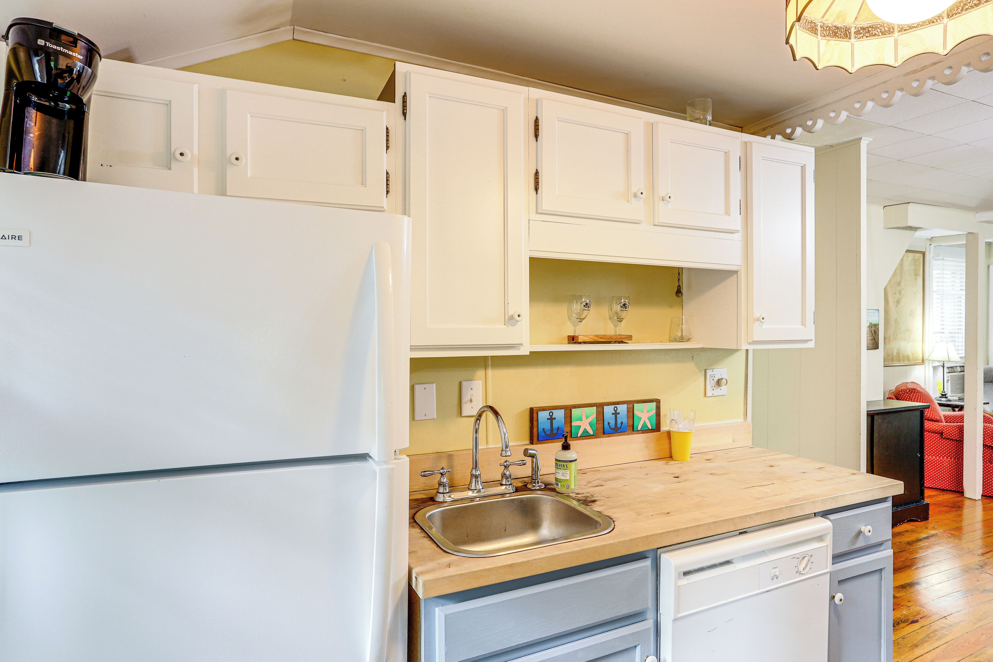 A kitchen with white cabinets, a stainless steel sink, and a coffee maker.