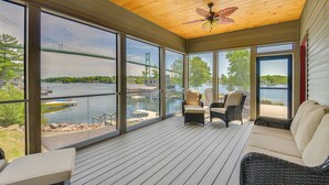 Une vaste terrasse offrant une vue sur un pont et l’eau, aménagée avec des fauteuils et un canapé en osier.
