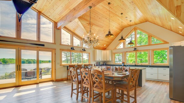 Une cuisine spacieuse, dotée de grandes fenêtres, d’un plancher en bois et d’un lustre.
