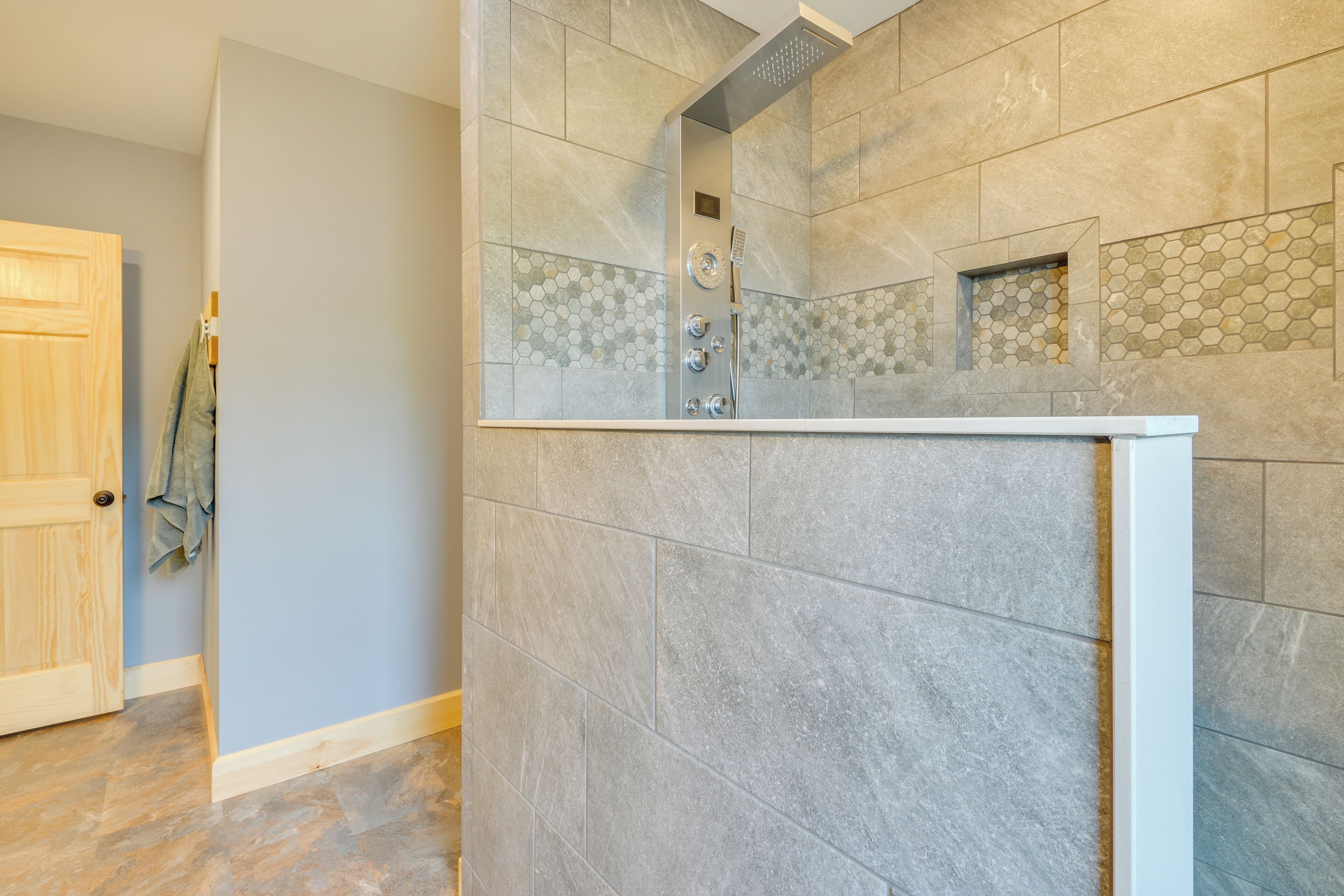 A bathroom with a shower, tiled walls, and a wooden door.