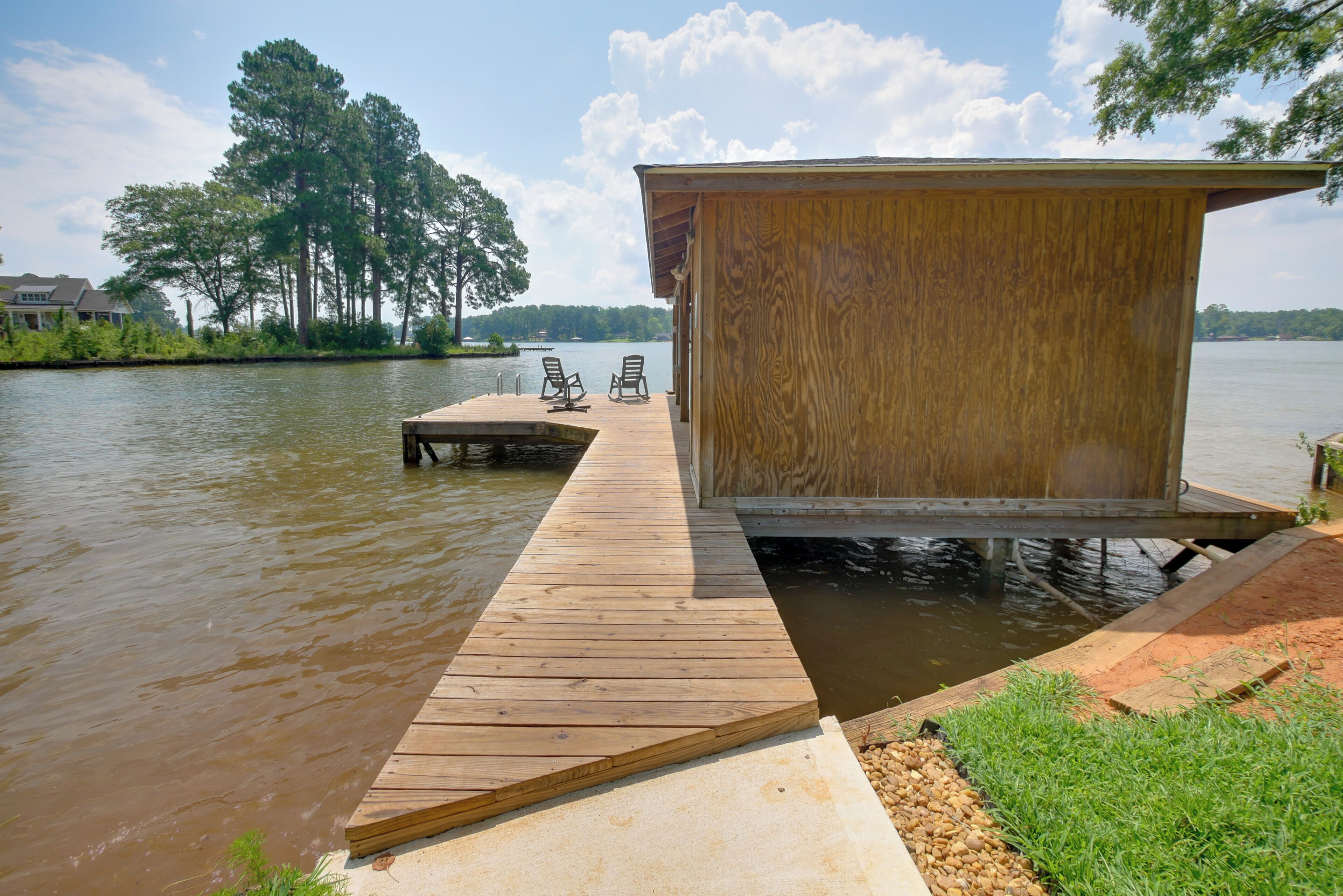 A wooden dock extending into a lake with a small wooden structure at the end.