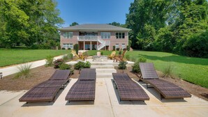 A two-story house with a front porch, a stone fireplace, and four sun loungers.