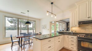 A modern kitchen with a large island, white cabinetry, and a built-in oven.