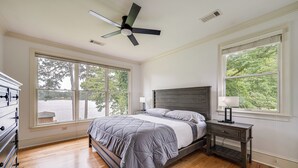 A bedroom with a bed, a nightstand, a dresser, and a ceiling fan.