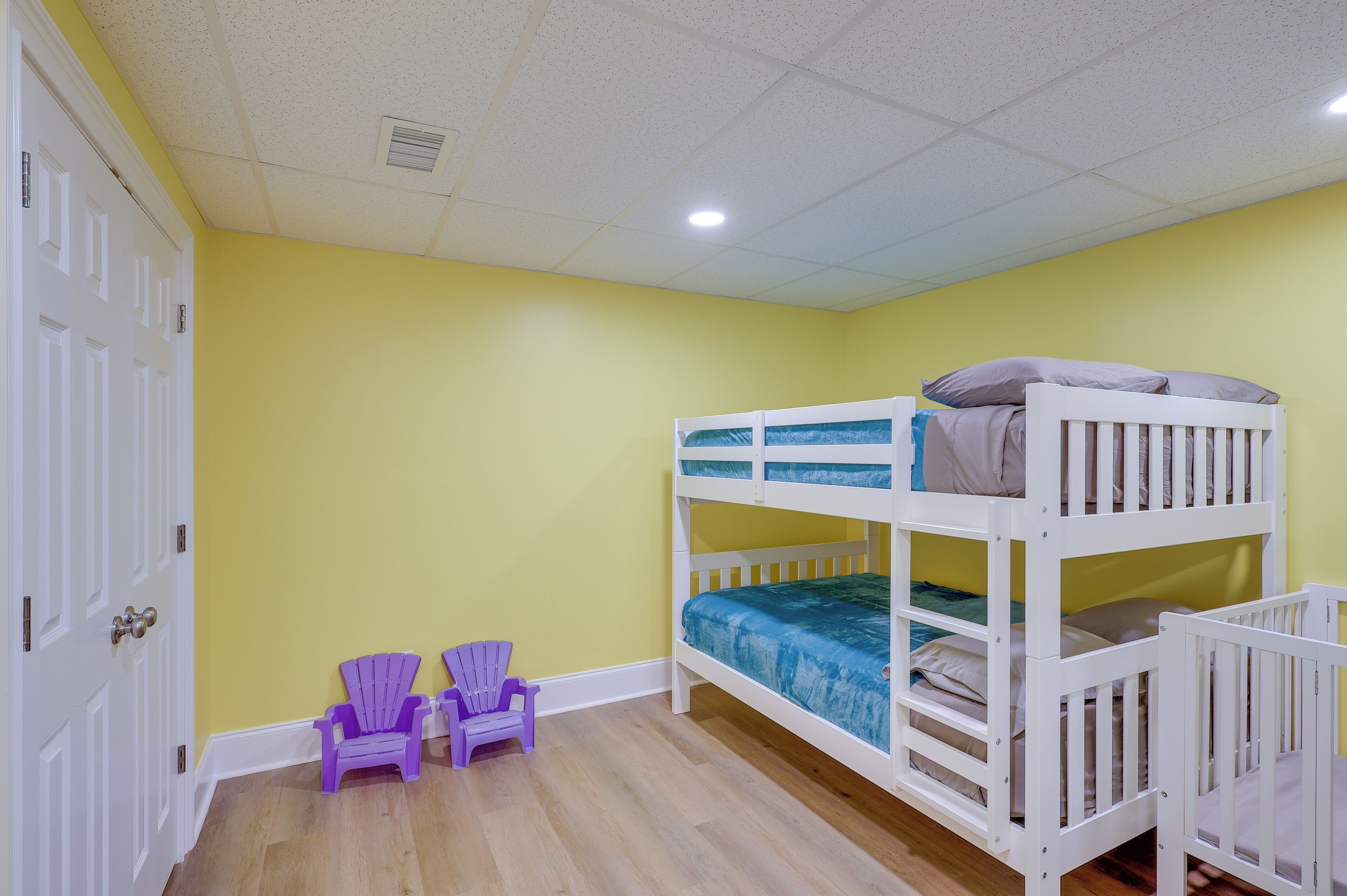 A room with a bunk bed, two purple chairs, and a white door.