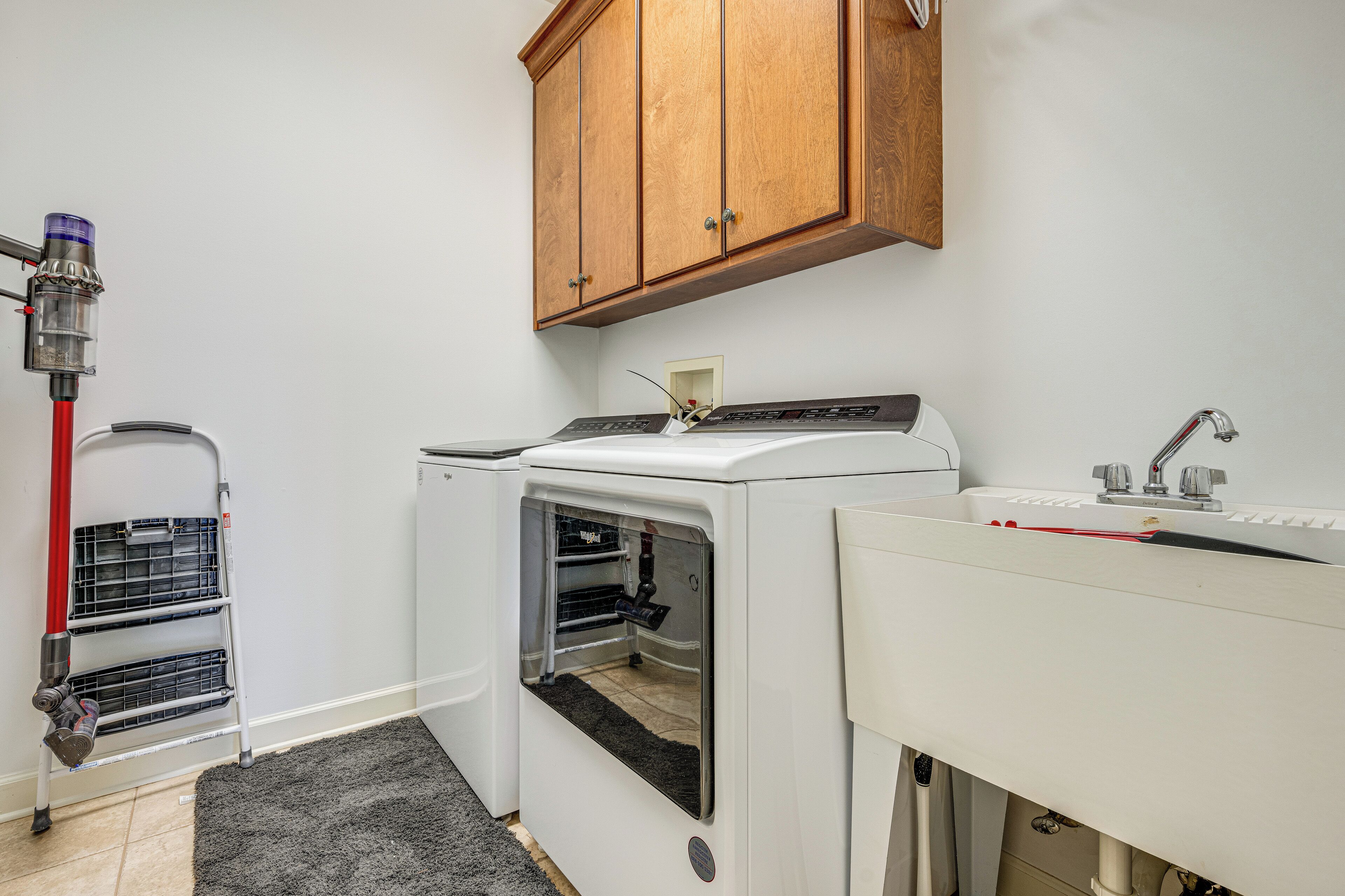 A laundry room with a washing machine, dryer, and a sink.