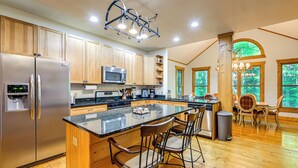 A modern kitchen with wooden cabinets, stainless steel appliances, and a central island with bar stools.