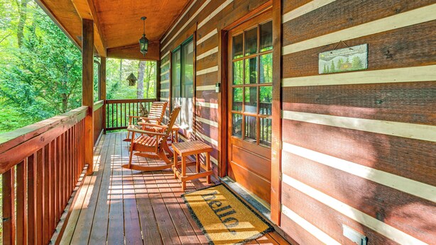 A wooden cabin with a porch, rocking chairs, and a welcome mat.