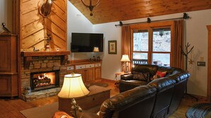 A cozy living room with a fireplace, leather sofa, and a flat-screen TV.