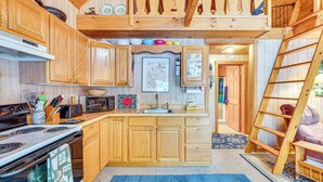 A kitchen with wooden cabinets, a stove, and a microwave. There is a ladder leaning against the wall and a blue rug on the floor. - Denmark Waterfront Cabin w/ Dock & Charcoal Grill! (Denmark)