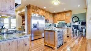 Una cocina amplia con armarios de madera, un refrigerador de acero inoxidable y una encimera de granito.