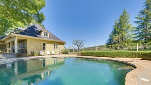 Una casa con piscina, un porche cubierto y un césped bien cuidado.