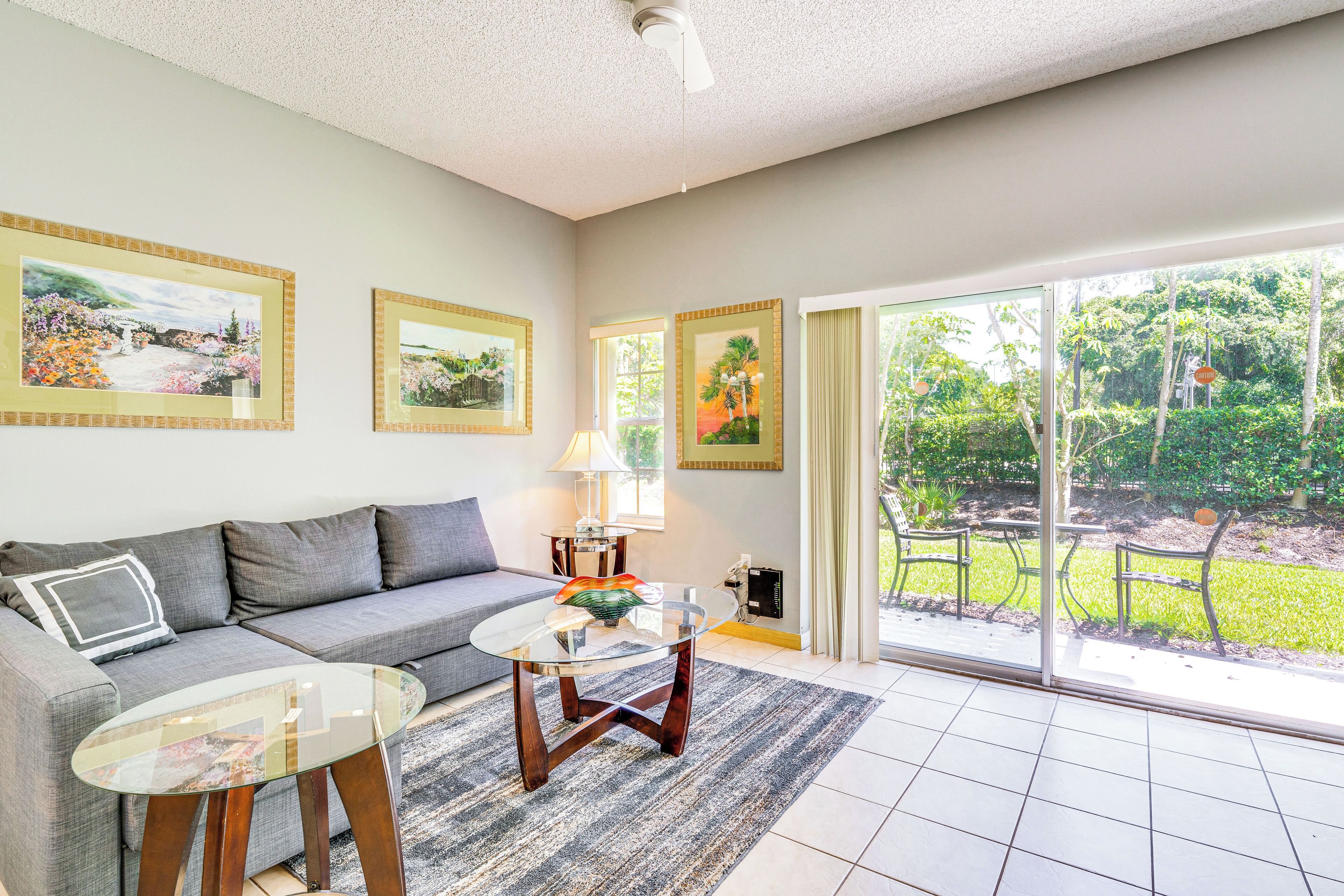 A living room with a sofa, a glass coffee table, and framed artwork on the wall.