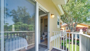 Une terrasse extérieure couverte, avec une porte-fenêtre coulissante donnant accès à une salle de bain.