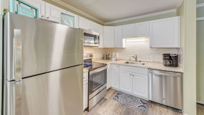 A kitchen with white cabinets, stainless steel appliances, and a backsplash. - 1 Mi to Beach, Pool Access: Hilton Head Island Gem (Hilton Head Island)