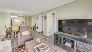 A living room with a sofa, coffee table, and TV stand. There is a dining area with chairs and a table. A laundry area with a washing machine and dryer is visible. - 1 Mi to Beach, Pool Access: Hilton Head Island Gem (Hilton Head Island)