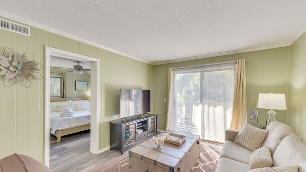 A living room with a sofa, a coffee table, a TV, and a bed in the adjacent room. - 1 Mi to Beach, Pool Access: Hilton Head Island Gem (Hilton Head Island)